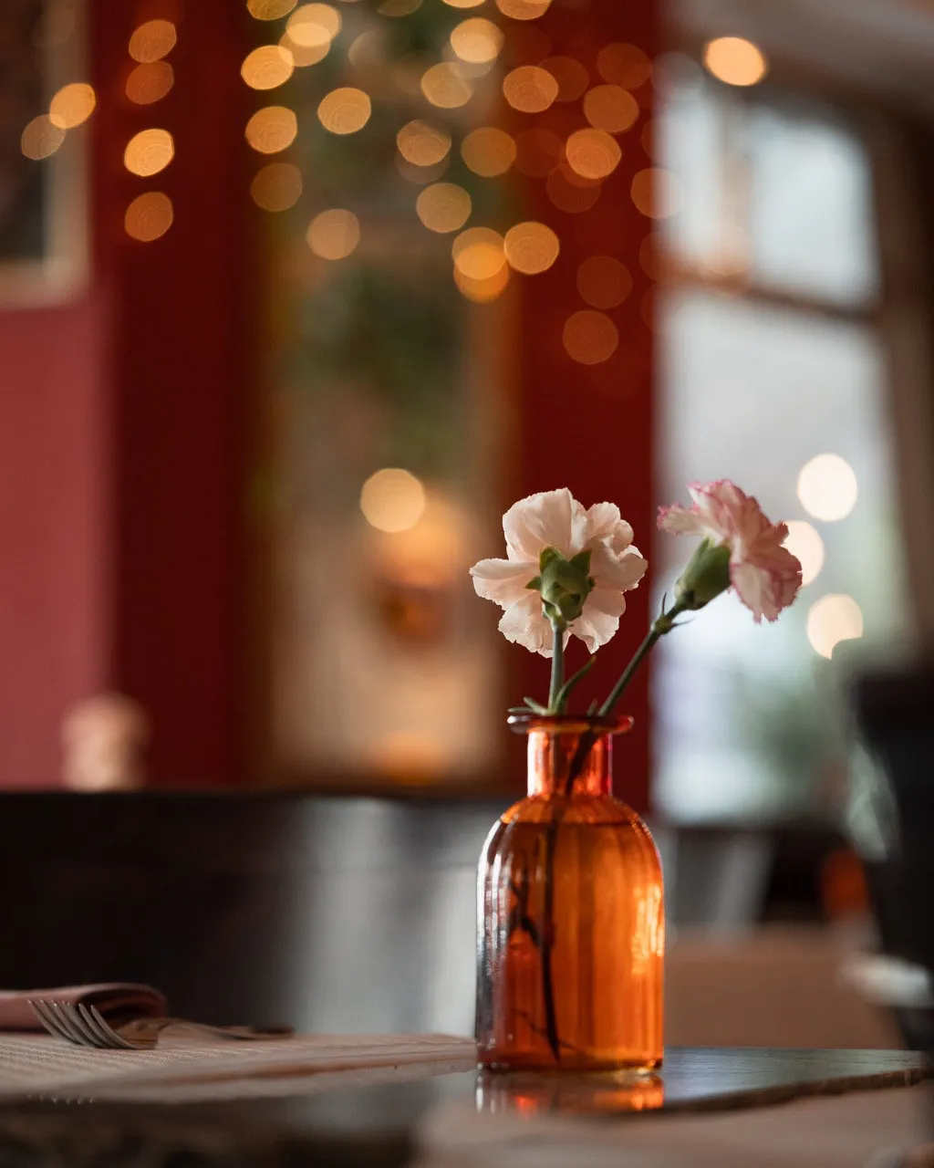 Gemütliches italienisches Restaurant mit eingedeckten Holztischen, Blumen und mediterranem Ambiente