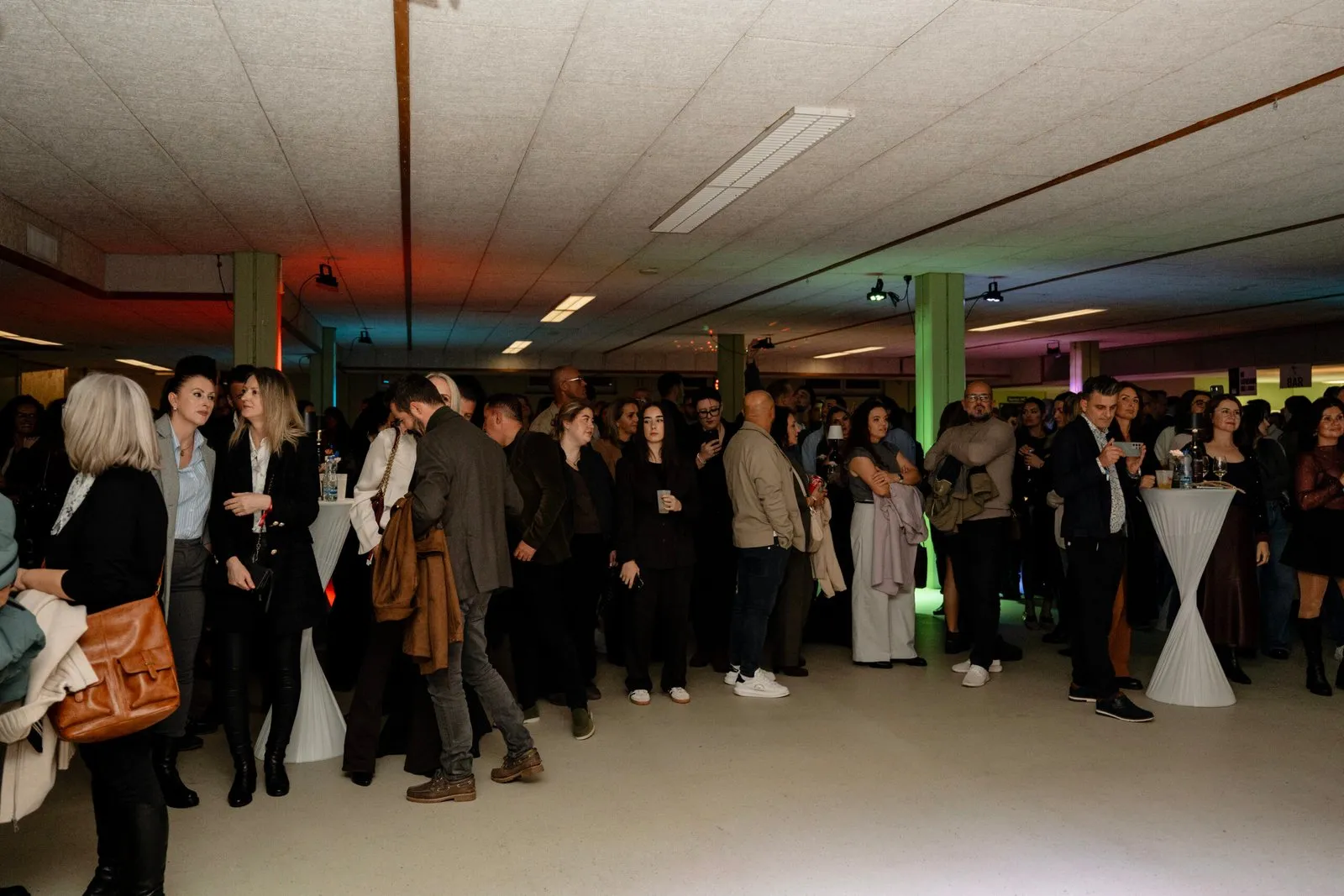 Ospiti in piedi ai tavolini alti nel foyer della Stadthalle Dietikon durante l’intervallo