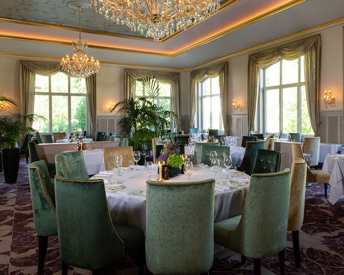 Grand Restaurant des Cresta Palace mit Kronleuchtern, runden Tischen und grünen Samtstühlen